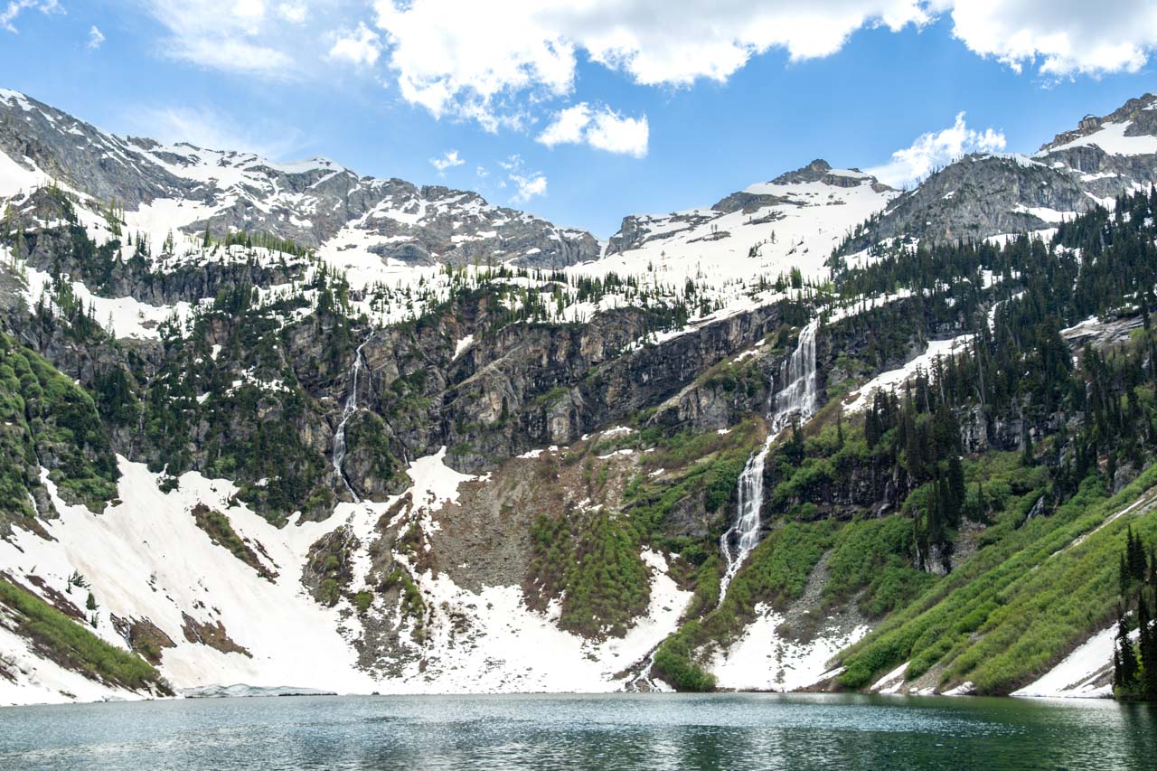Mountain lake with snow-melt waterfalls