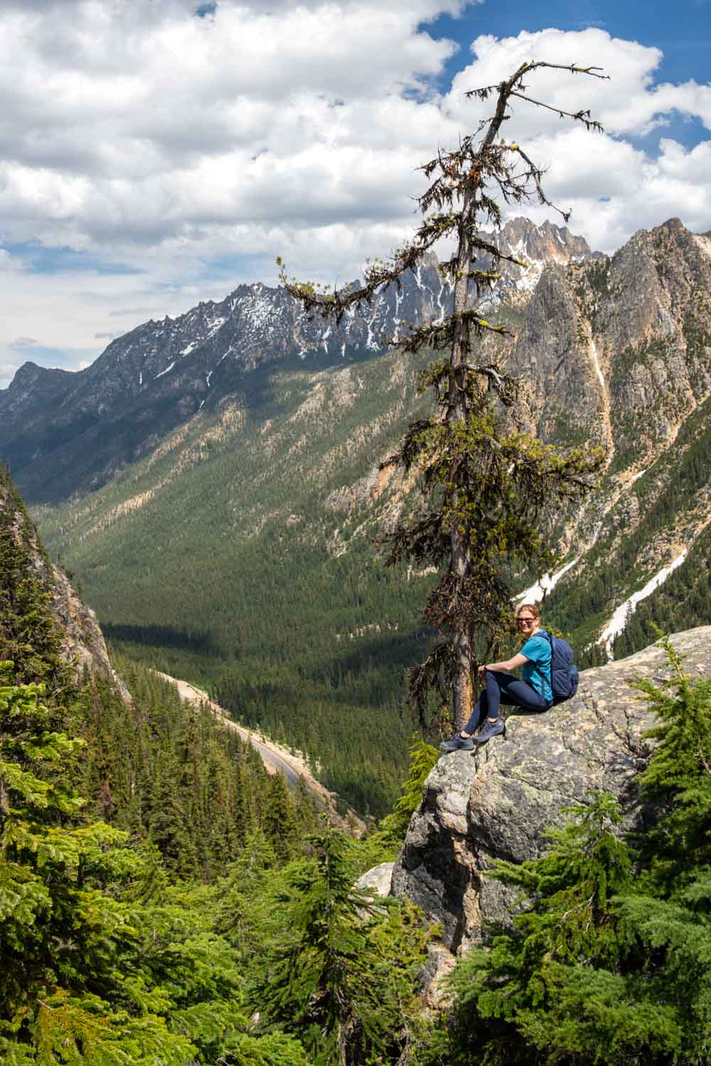 Woman looking out from a rocky outcrop to mountains across a deep valley
