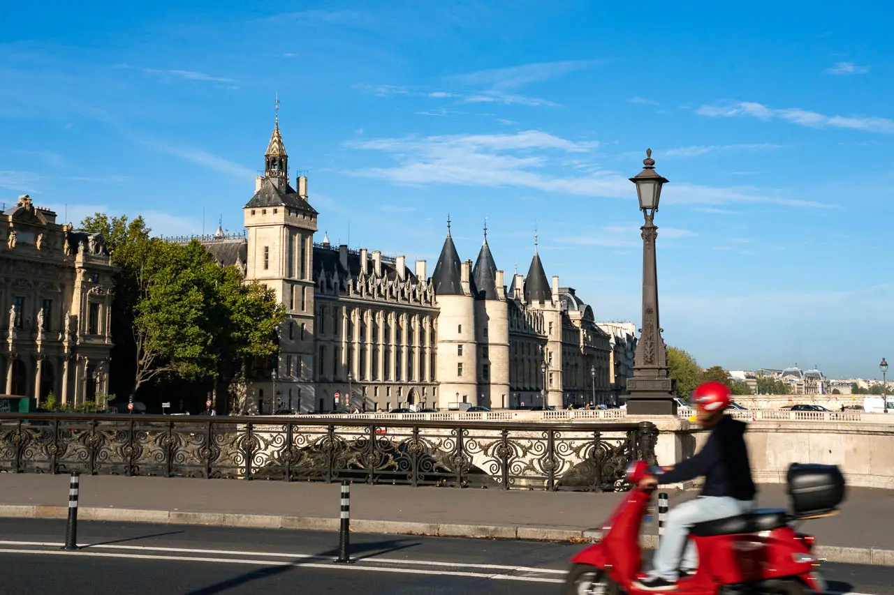 The Conciergerie viewed from Pont Notre-Dame with person on red scooter
