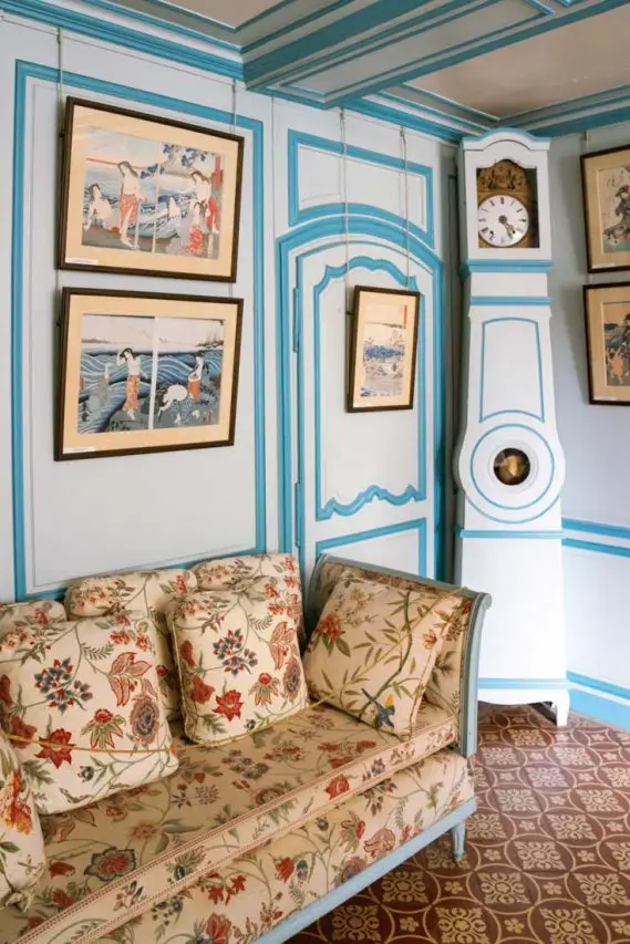 Blue sitting room with tall grandfather clock and Japanese woodblock artwork on the walls