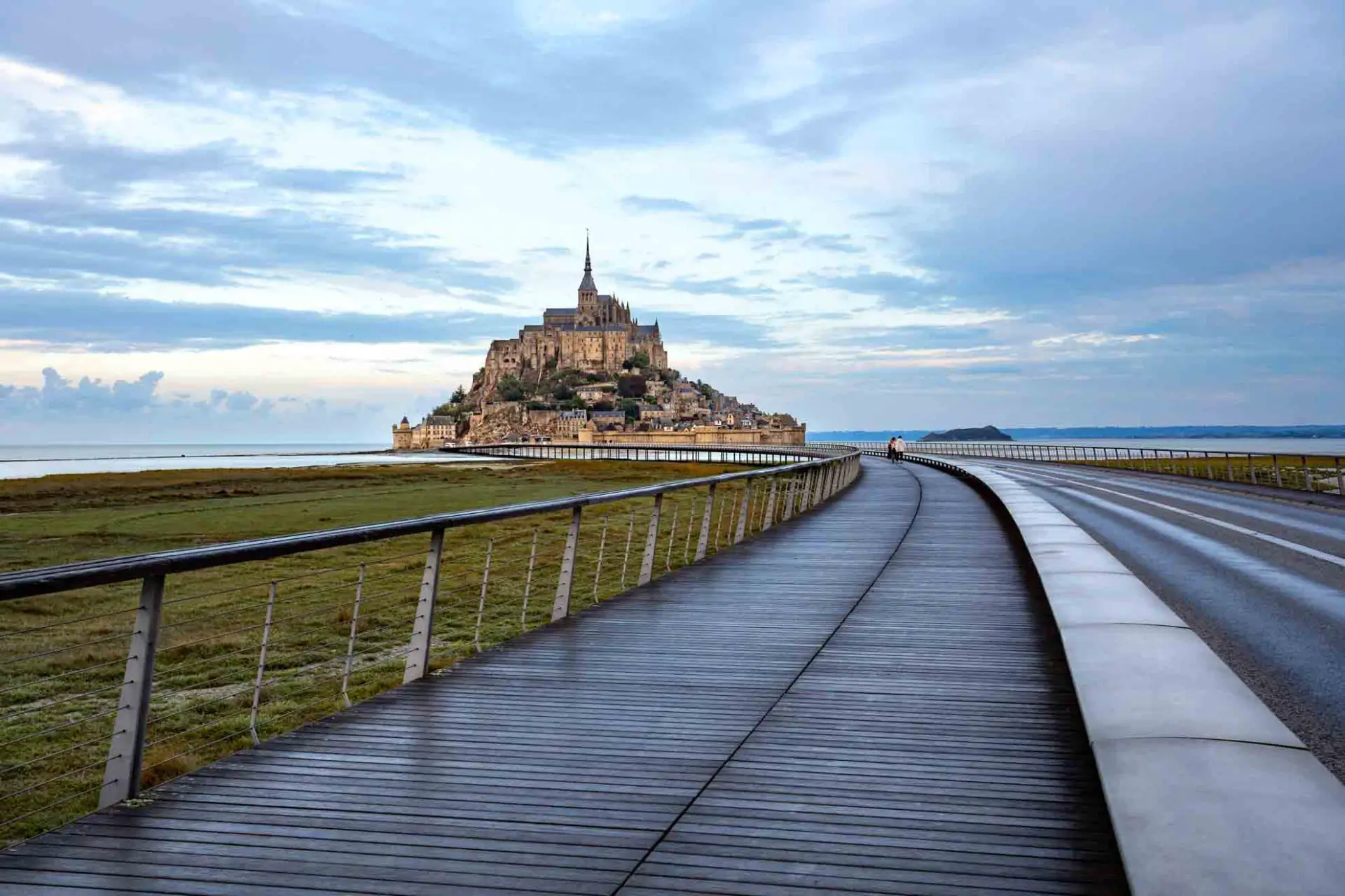Mont Saint Michel at dawn with causeway, wet with rain, in the foreground