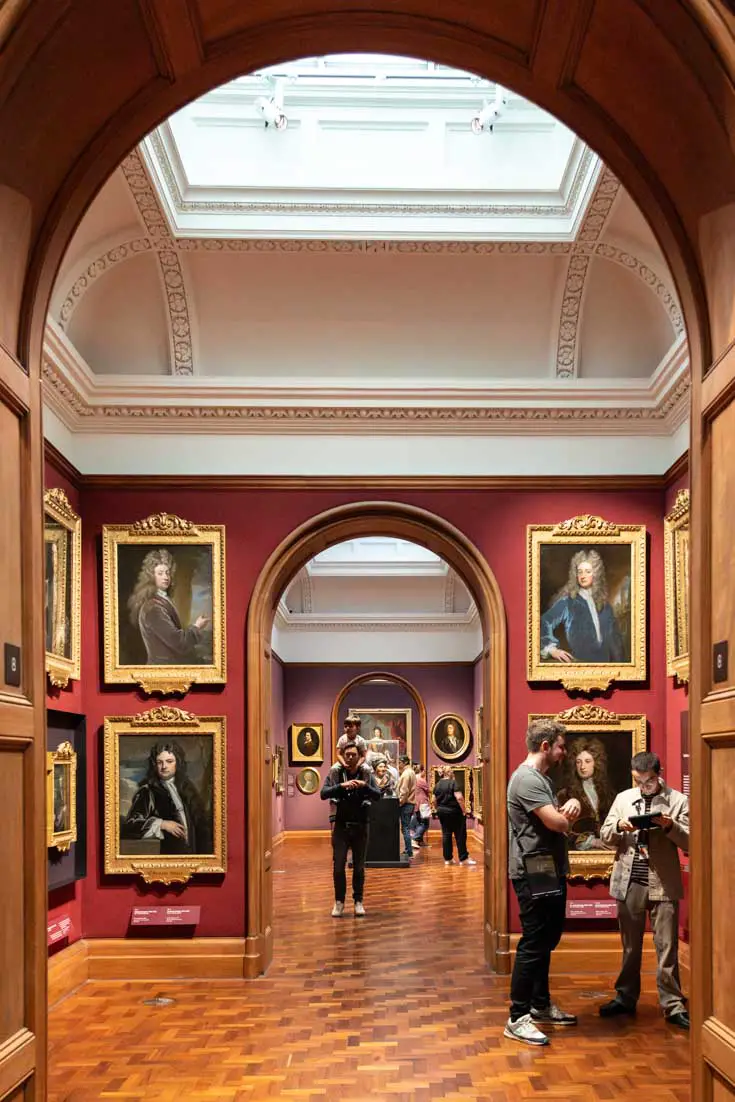 Photo framed by arched doorways leading between art galleries filled with portraiture