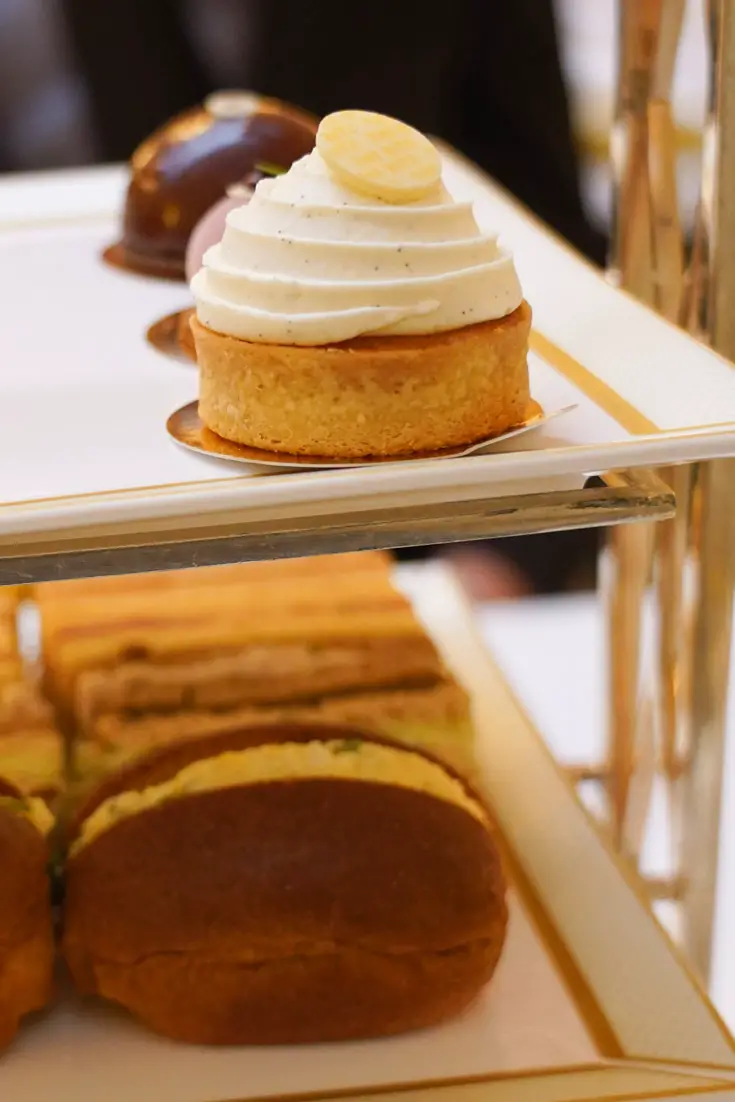 Small cakes and sandwiches on a white and gold tiered service