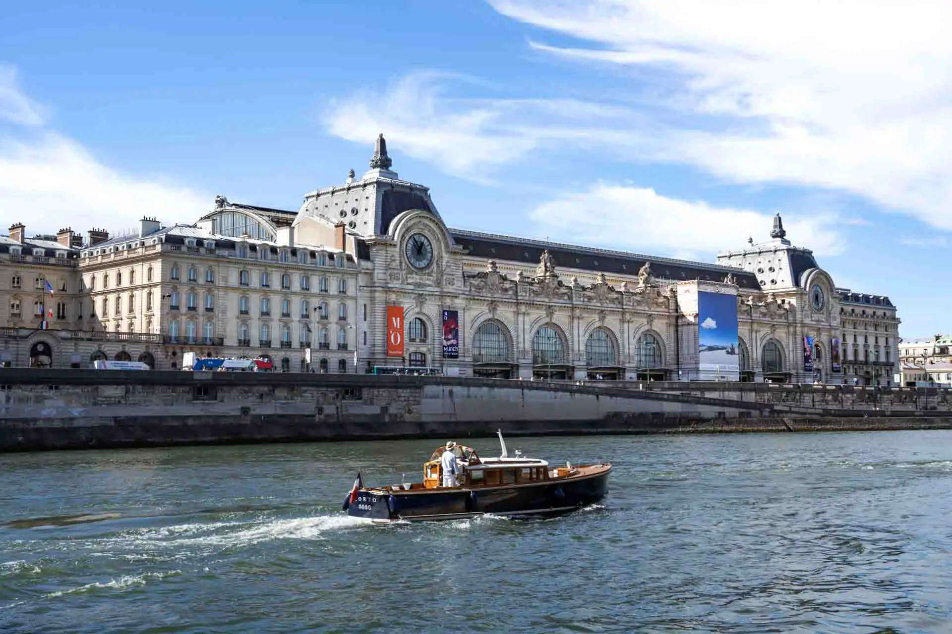 Wooden boat cruising along the River Seine passed a large Beaux-Arts building