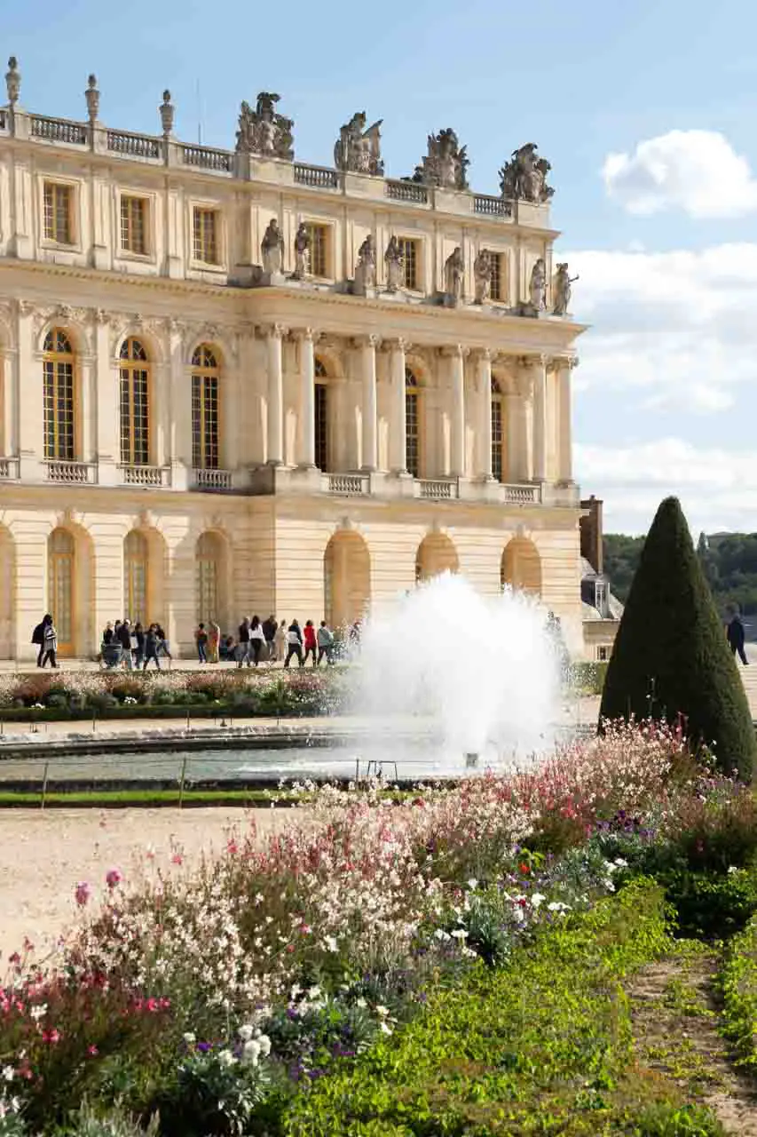 Palace of Versailles with fountain and flower gardens in foreground