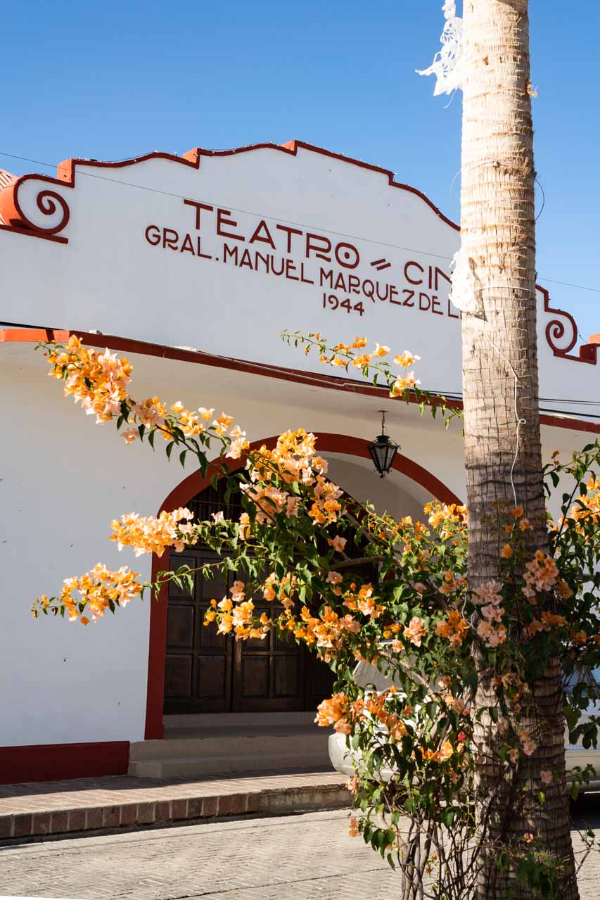 Historic Spanish colonial theatre building with orange bouganvillas in the foreground