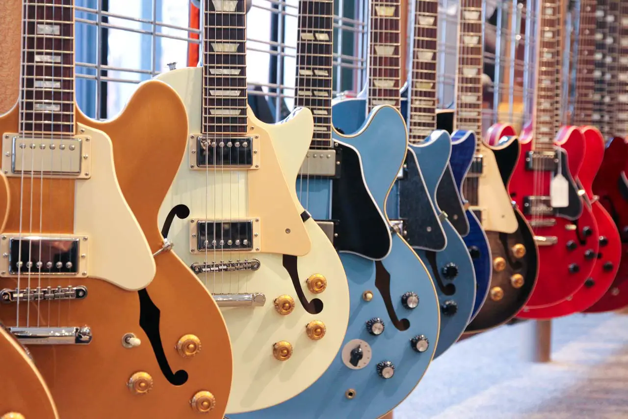 Line up of guitars in cream, blue and red, inside the Gibson Guitar Factory