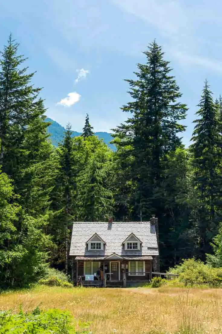Cute cottage-looking ranger station backed by forest and mountain peaks