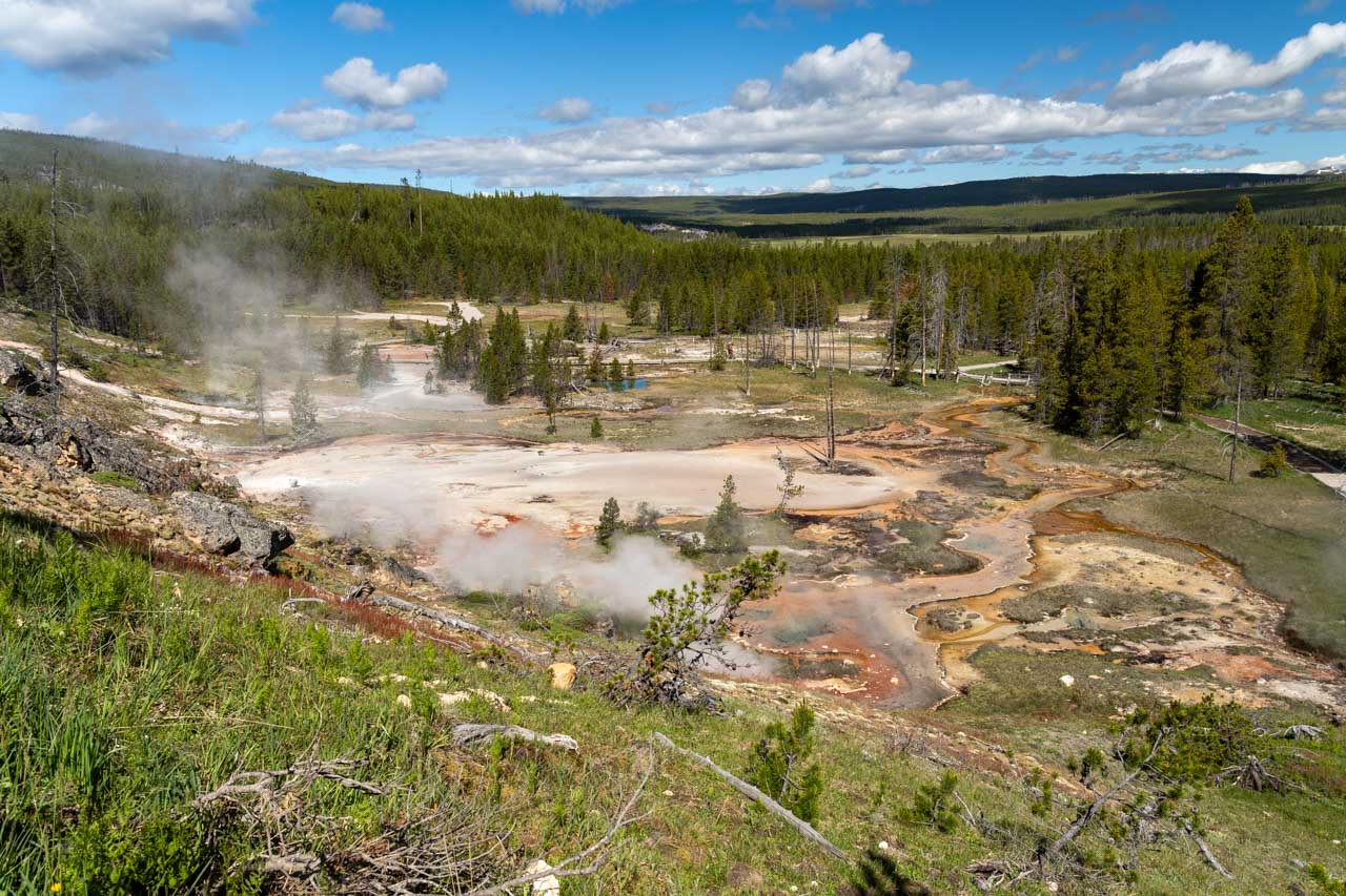 Overlook vista over Artists Paintpots, a geothermal area, with forest and mountains in the distance