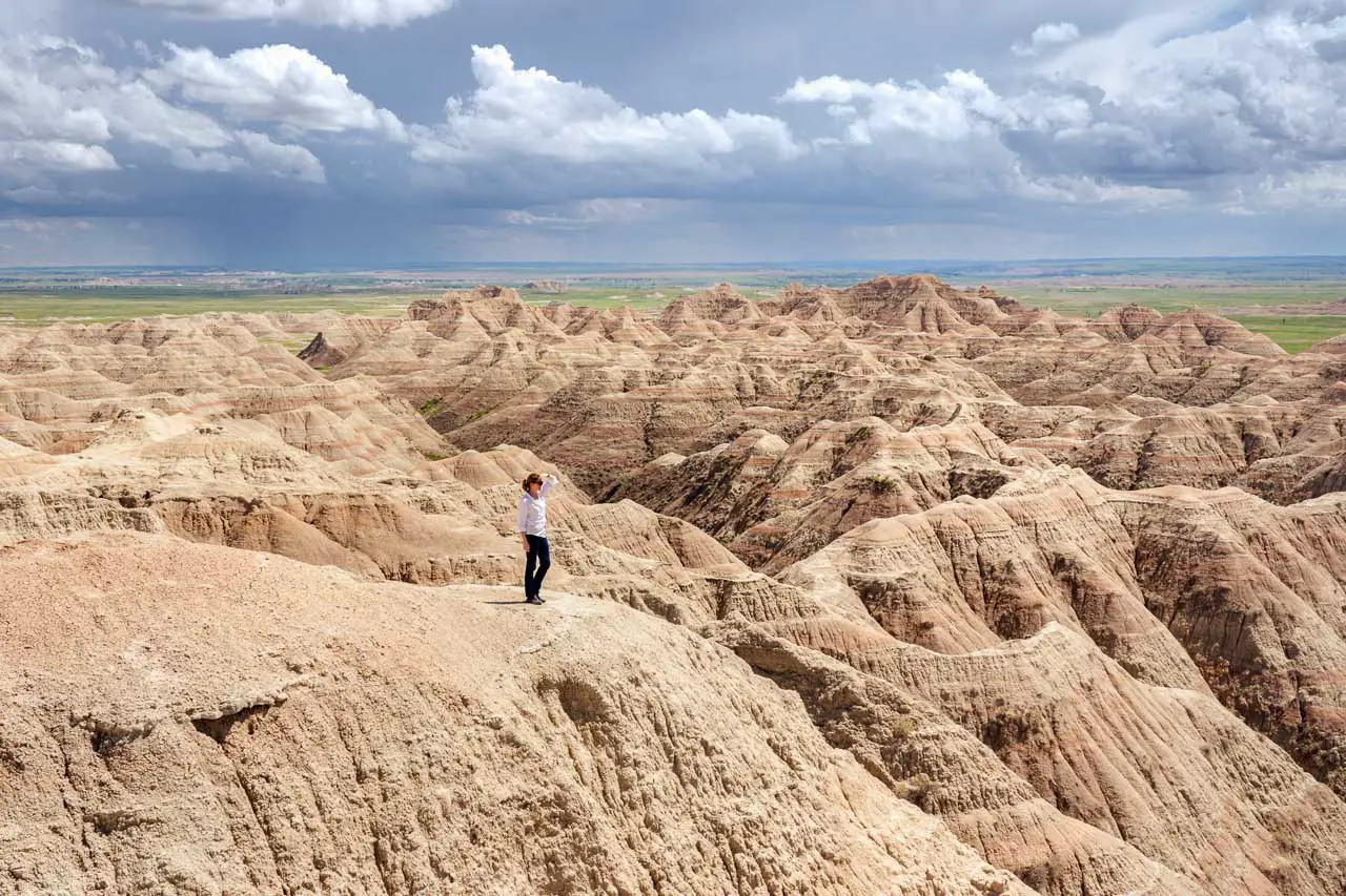 Woman standing on the edge of Badlands with storm in the distance