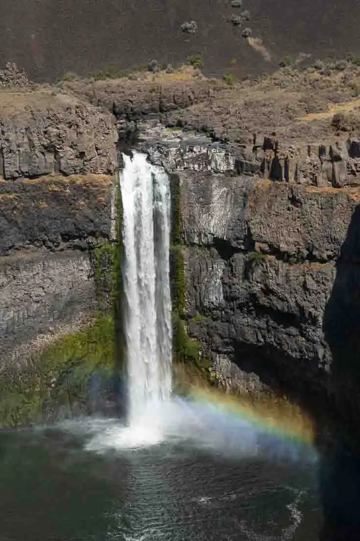 Image of waterfall in rocky cataract, with a rainbow showing in the mist