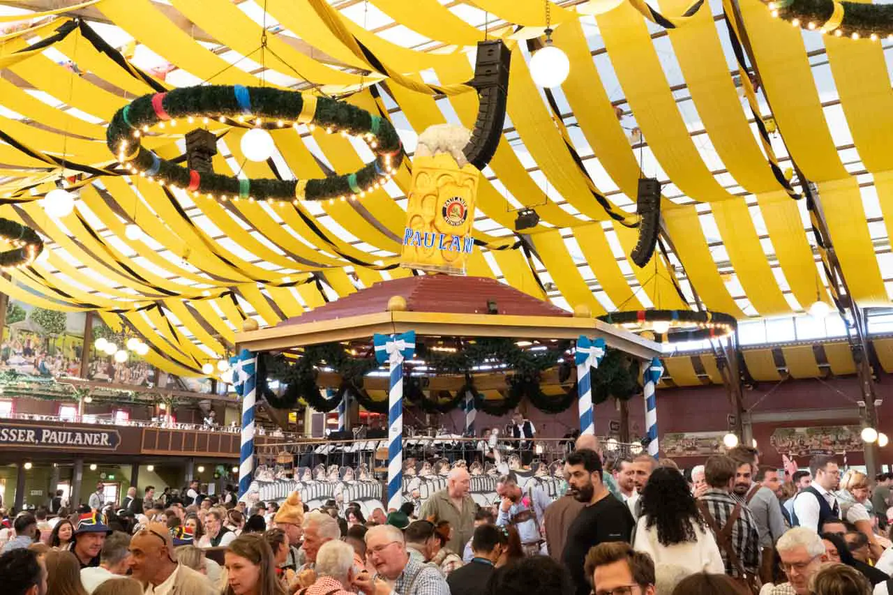 Oktoberfest beer hall with yellow ceiling decorations and bandstand