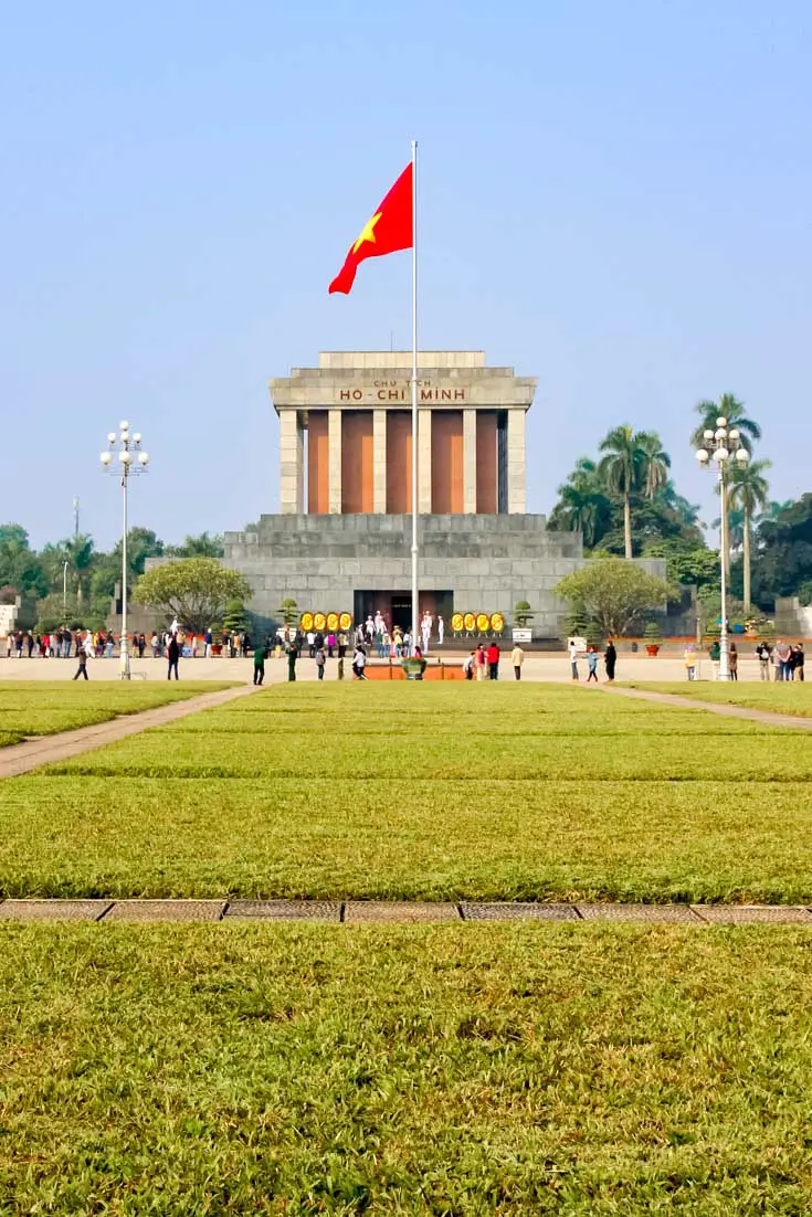 Ho Chi Minh's Mausoleum with Vietnamese flag and lawn in foreground