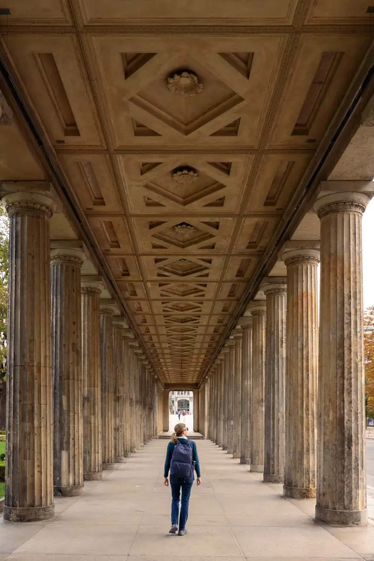 Woman with backpack walking through grand colonade
