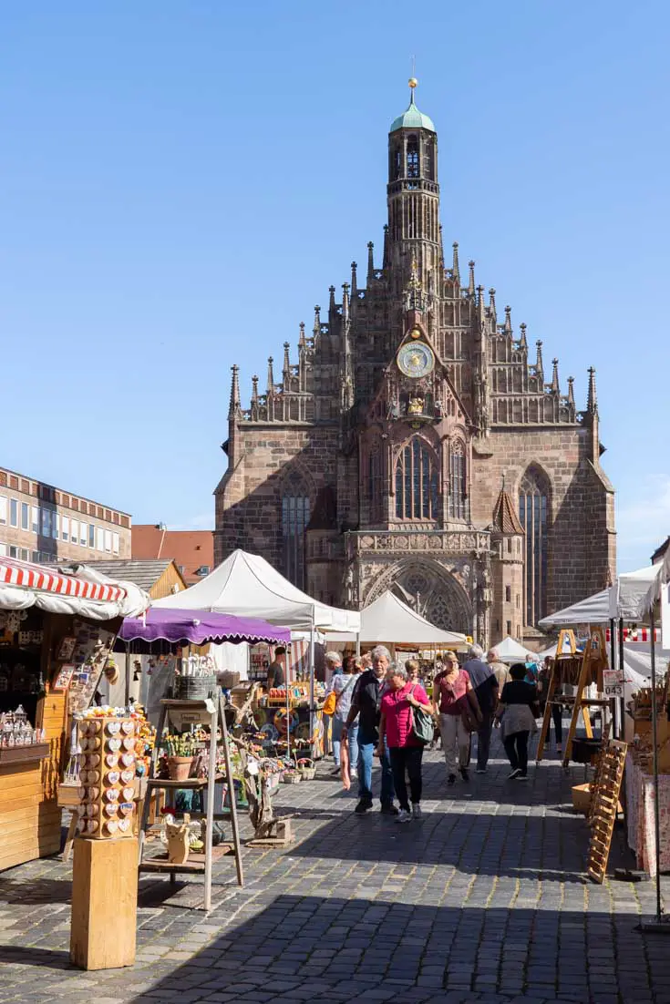 Outdoor market on sunny day with large gothic church in the background