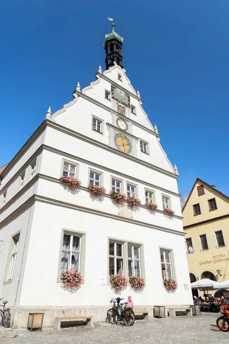 A traditional white building with flower boxes in the windows and a central clock