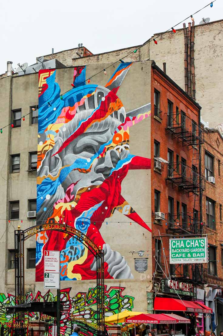 Multi-coloured mural of the Statue of Liberty on the side of a brick building in Little Italy, NYC
