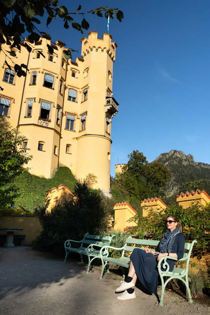 Woman sitting in afternoon sun in the garden of Hohenschwangau Castle