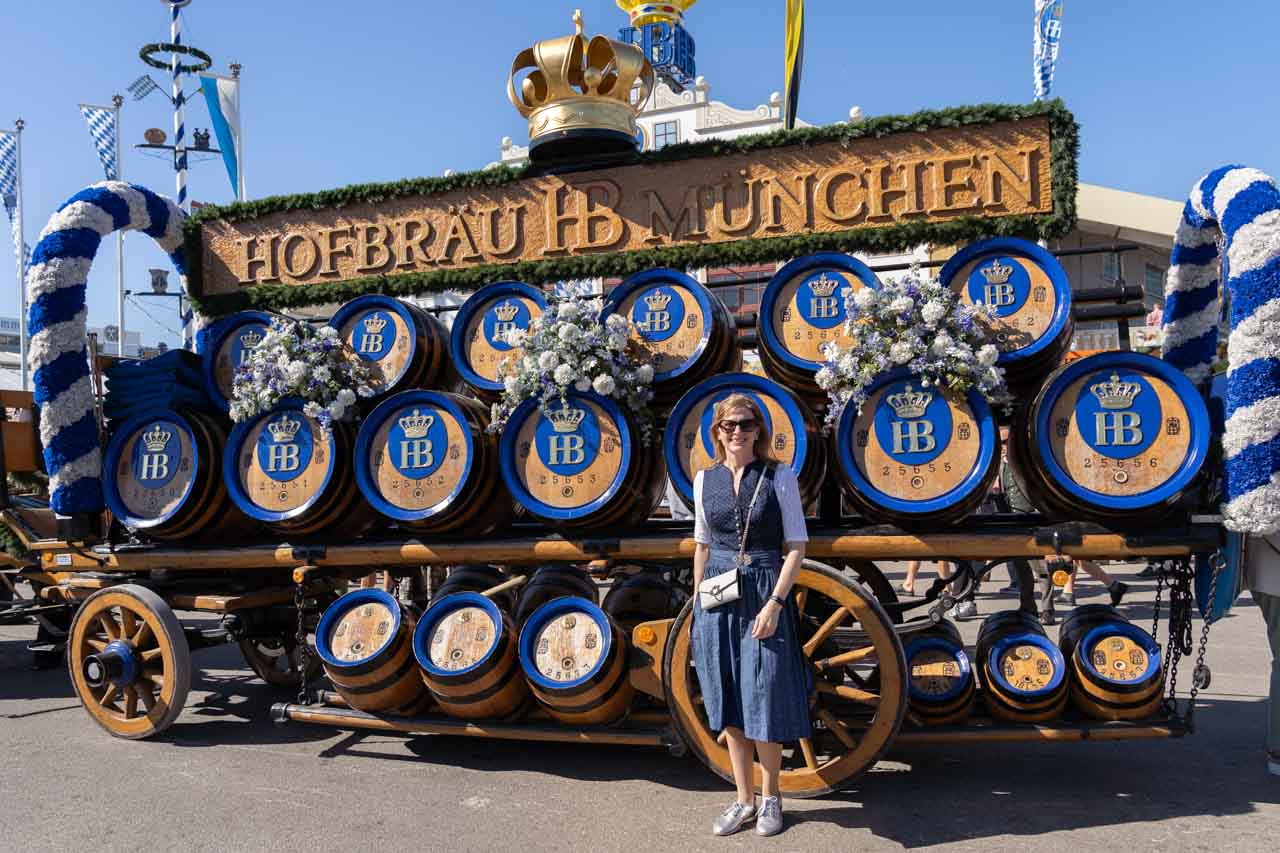 Woman in blue dirndl infront of kegs of Hofbräu beer
