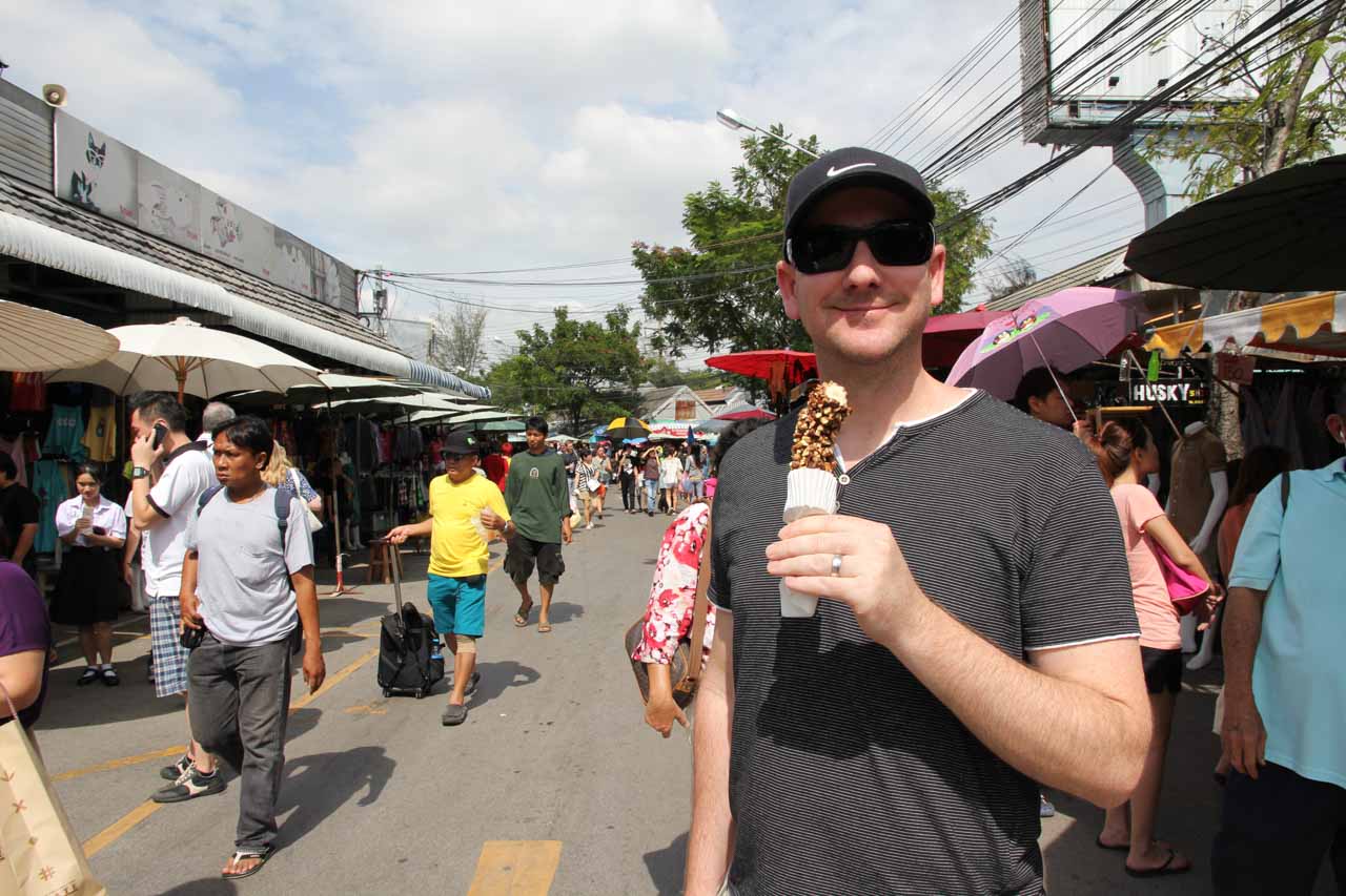 Man holding choc-covered frozen banana in an outdoor market