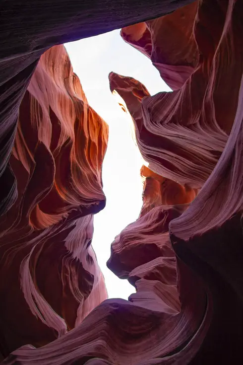 Red rocks of slot canyon forming a seahorse opening, when looking up at the sky
