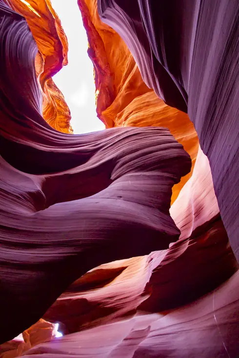 Slot canyon illuminated in red, purple and orange by sunlight on canyon walls