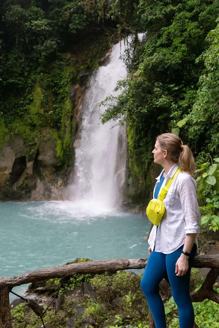 Woman standing near waterfall with turquoise-coloured plunge pool