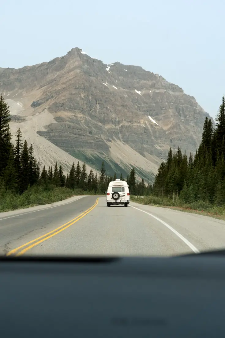 Photo of campervan driving through mountain scenery with dashboard in foreground