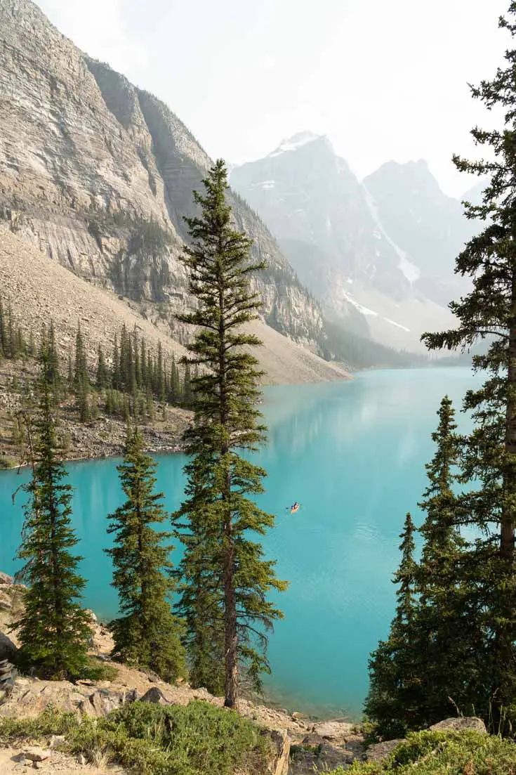 View over Lake Moraine with small orange canoe and mountains in the distance