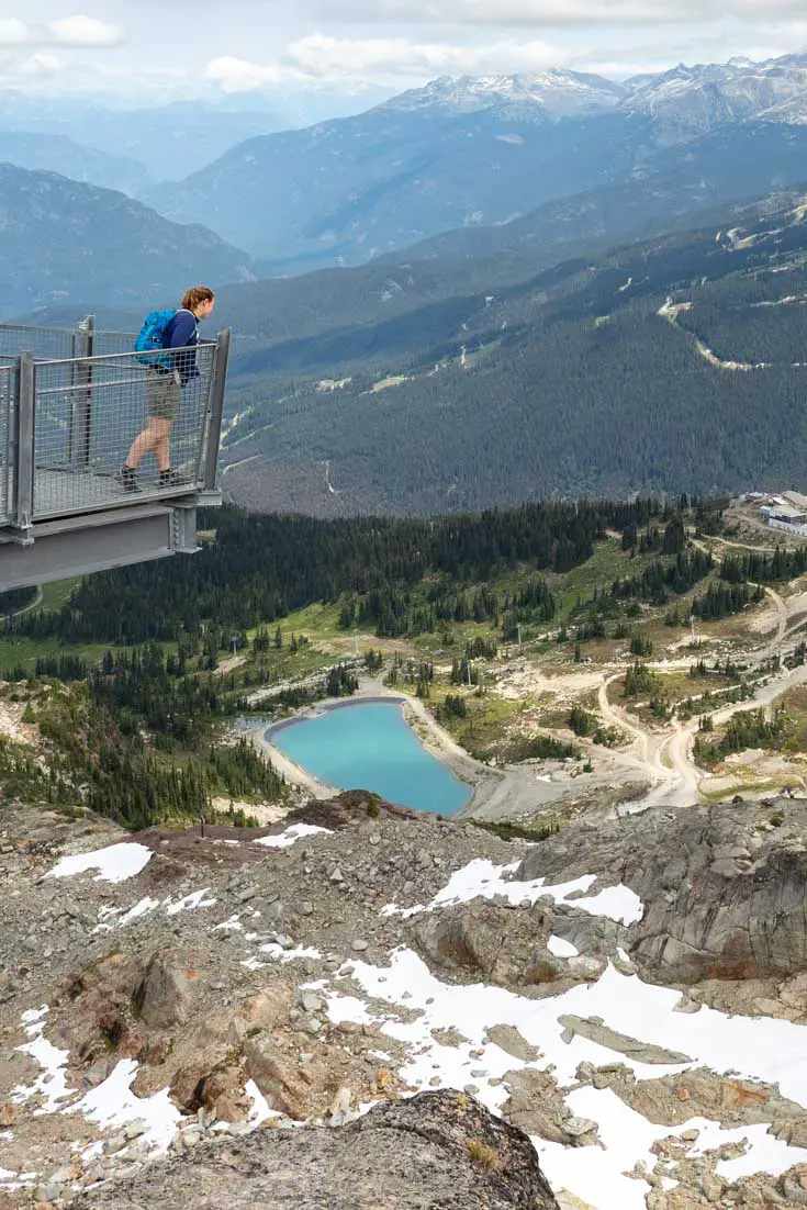 Woman looking over railing at view over mountains and valleys