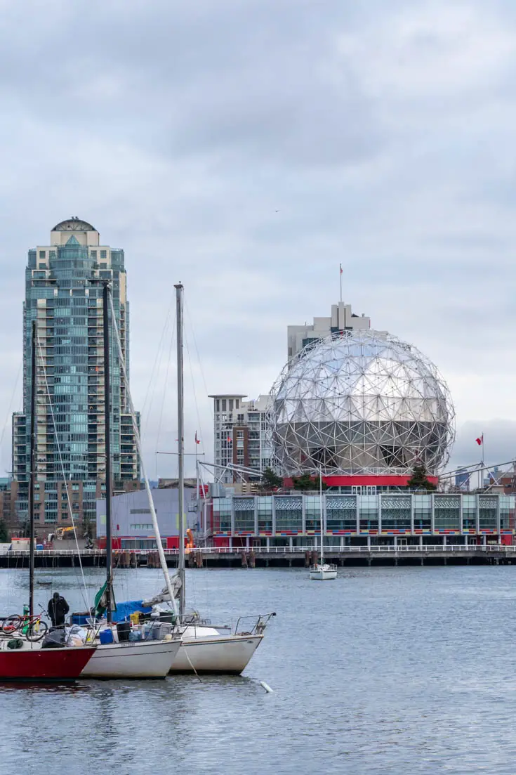 View across water with moored boats, and silver, spherical building on far shore