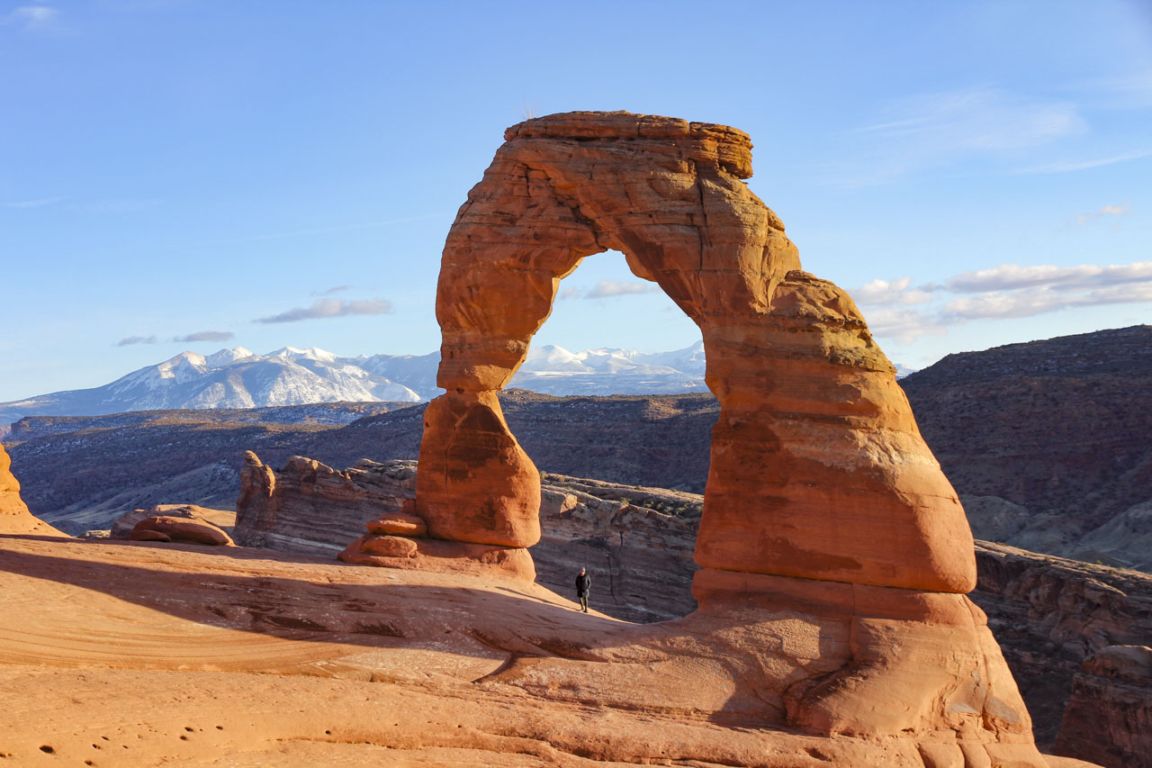 Madam ZoZo standing under Delicate Arch during golden hour on sunny November day