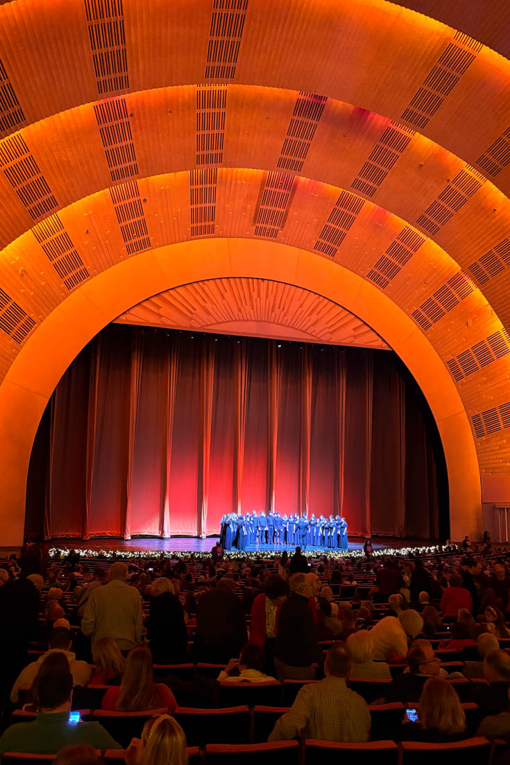 Choir on stage in Radio City Musical Hall, infront of red curtain and golden proscenium arch