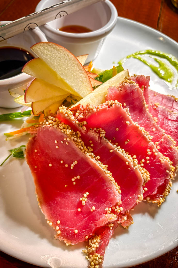 Seared, sesame-crusted tuna slices on a white plate