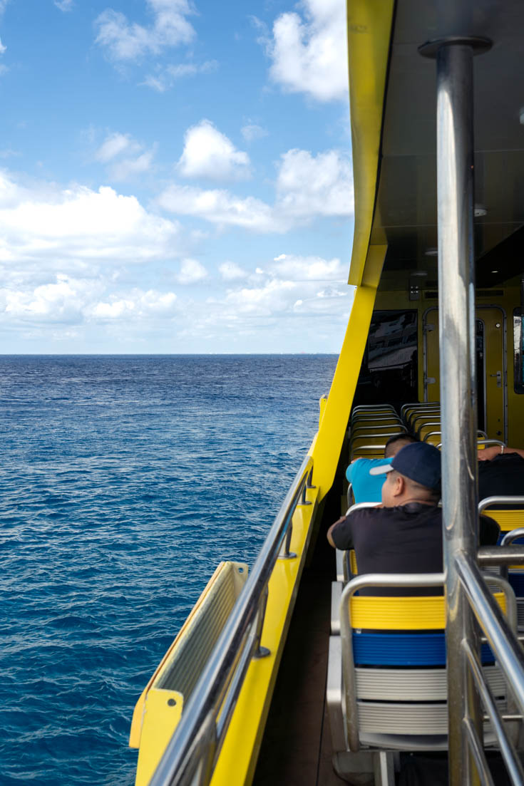 Man looking out from yellow ferry to blue sky and ocean