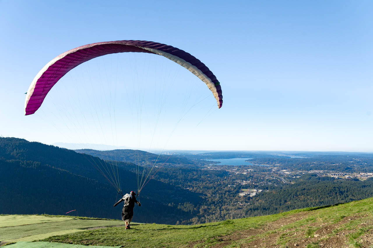 Paraglider launching from mountaintop on sunny day