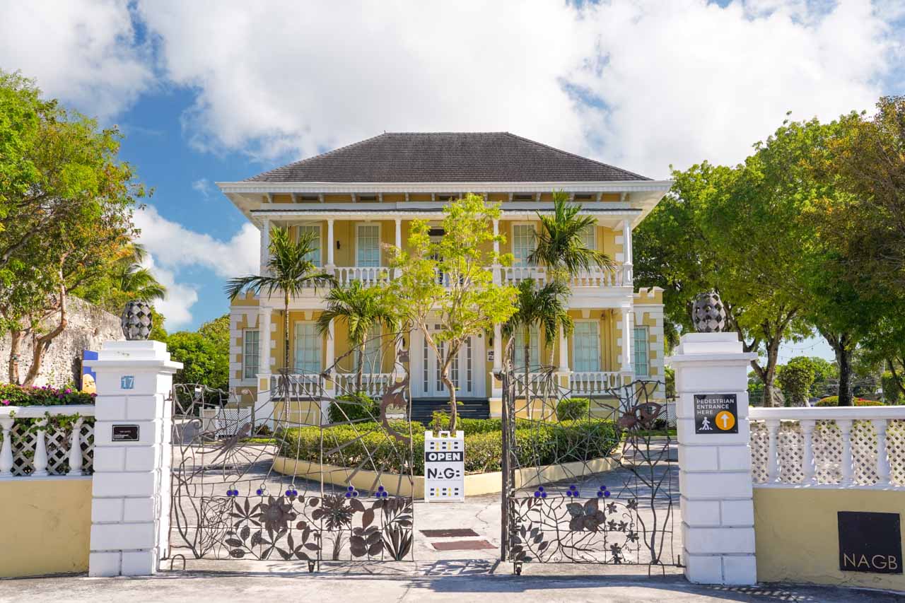 Yellow colonial mansion framed by decorative front gate