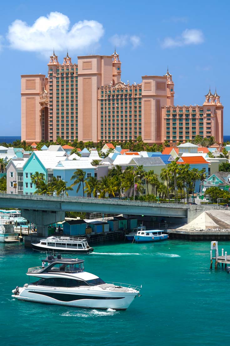Large salmon-coloured hotel with tropical water and large, luxurious boats in foreground