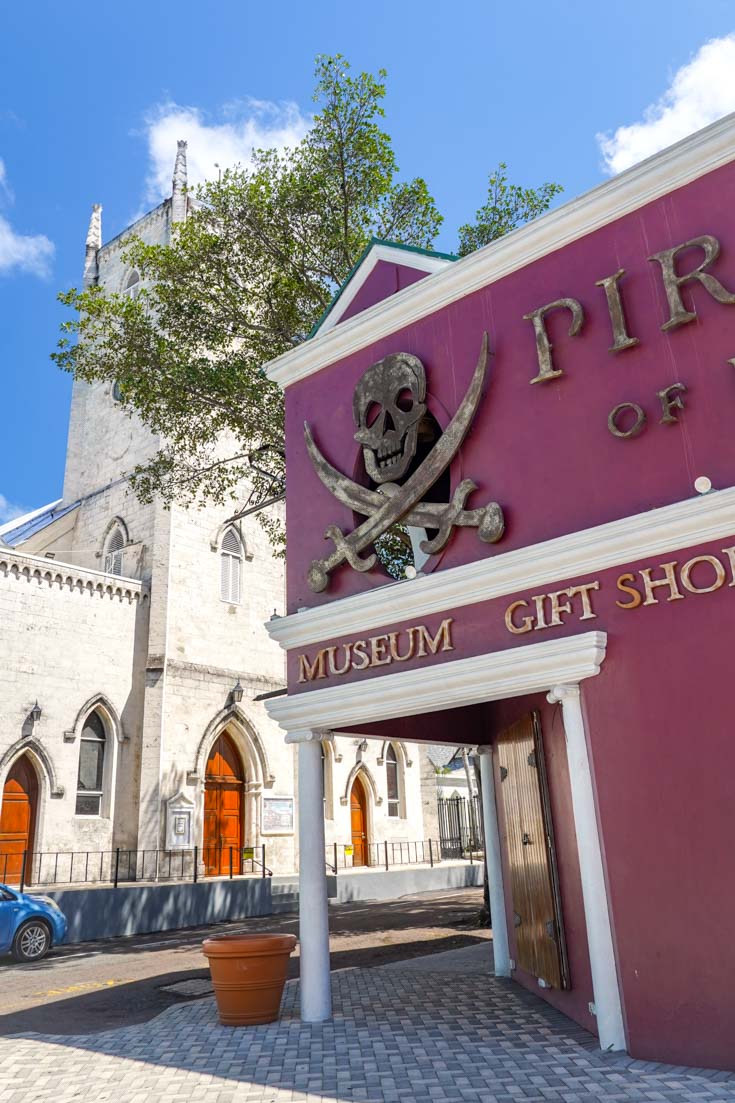 Magenta building with skull and crossbones above corner doorway, and church across the street