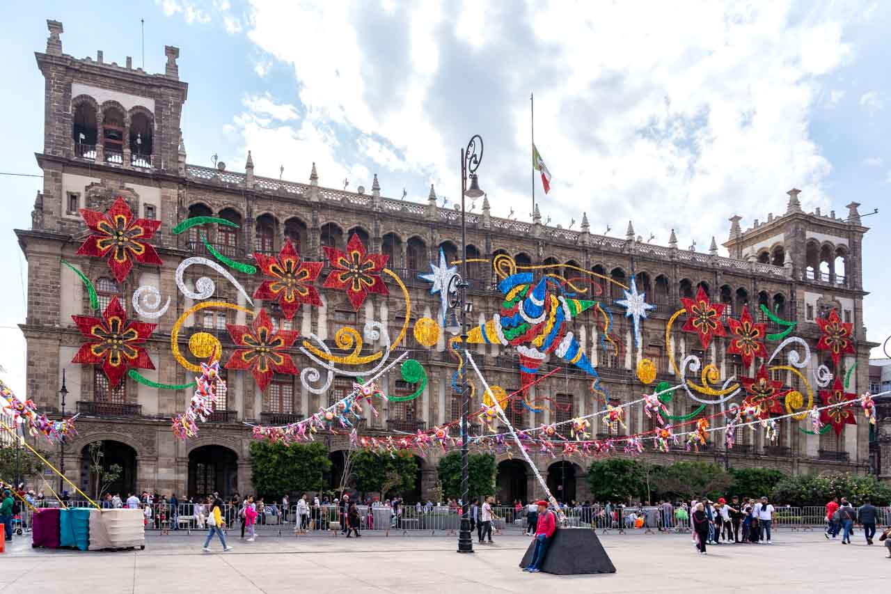 Large historic building decorated with tinsel in the shapes of poinsettias, piñatas and stars of Bethelem