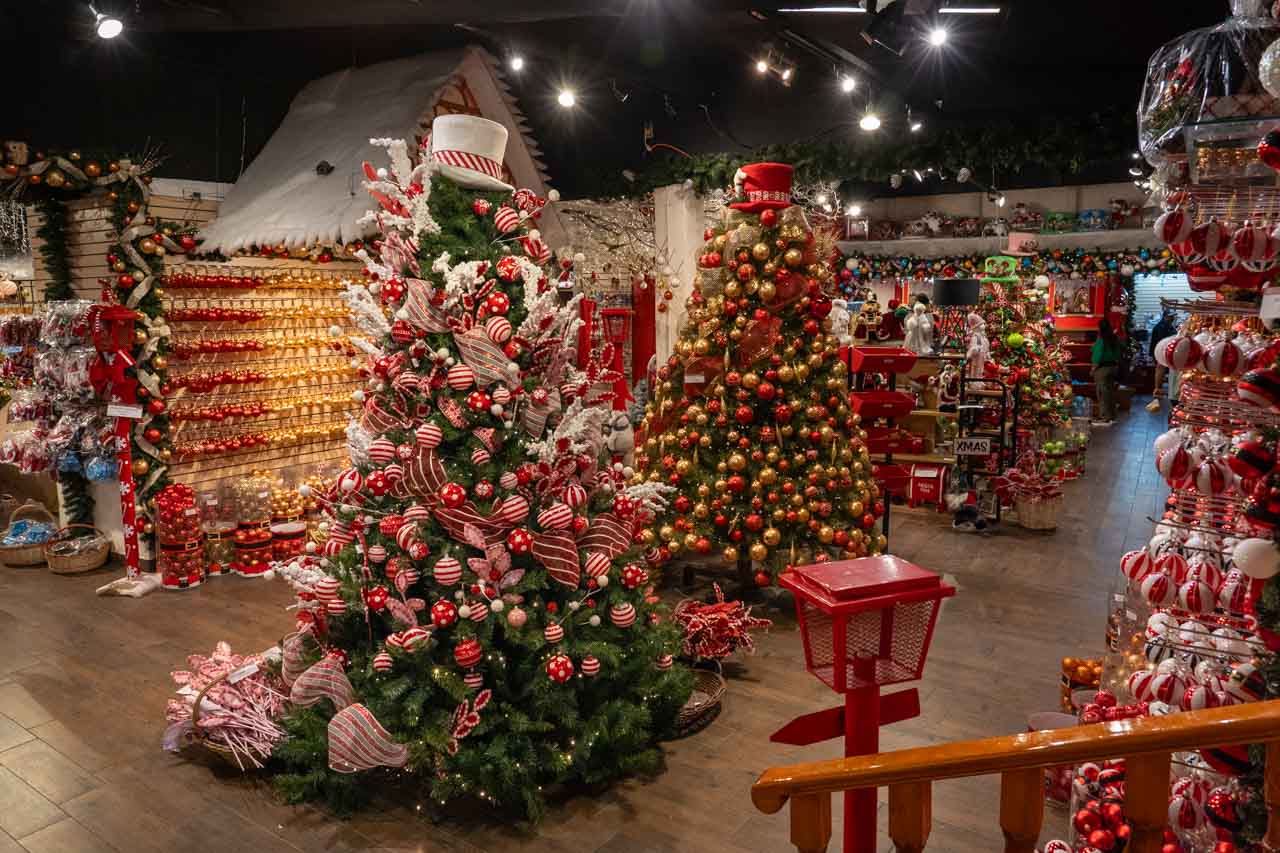 Inside of store selling Christmas decorations with themed Christmas trees in red and white, and red and gold decorations
