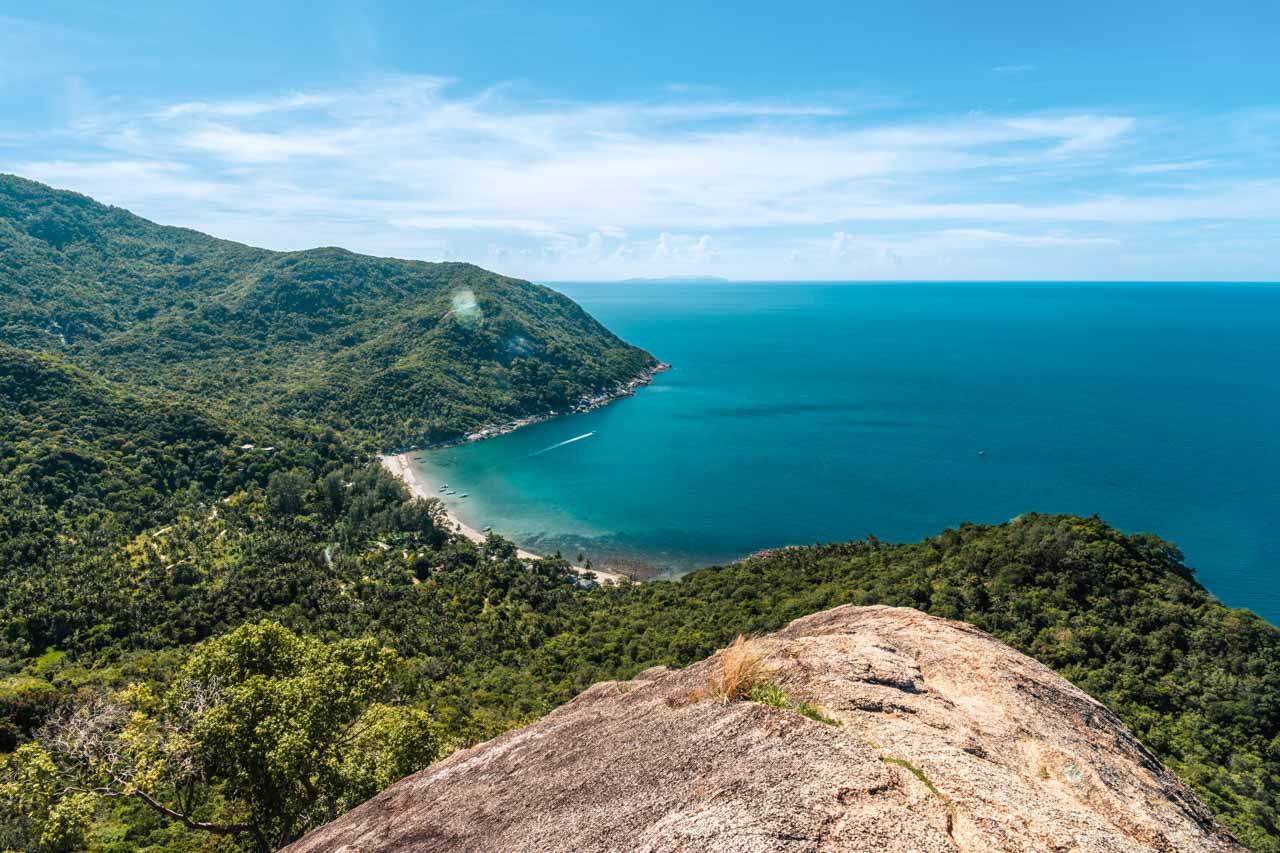 Bottle Beach from above, embraced by lush green forests, with vibrant tropical waters and azure sky on a summer day in Koh Phangan, Thailand.