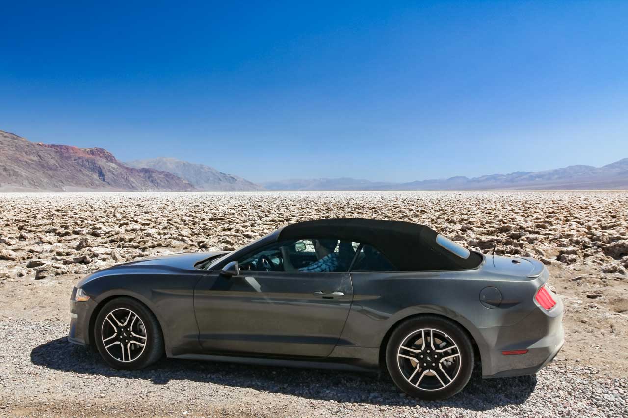 Silver mustang parked infront of Devil's Golf Course with distant mountains