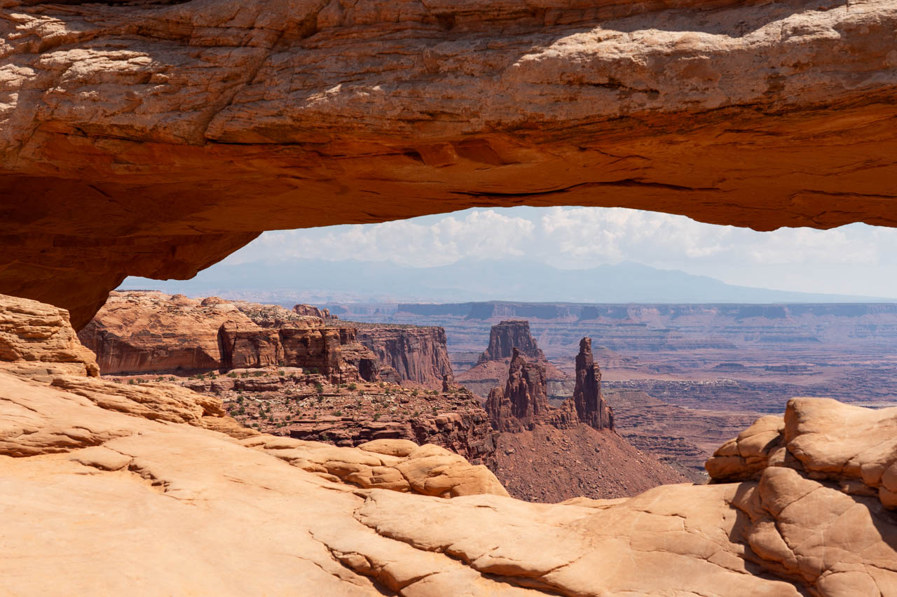 Distant rock spires and canyon viewed through wide sandstone arch