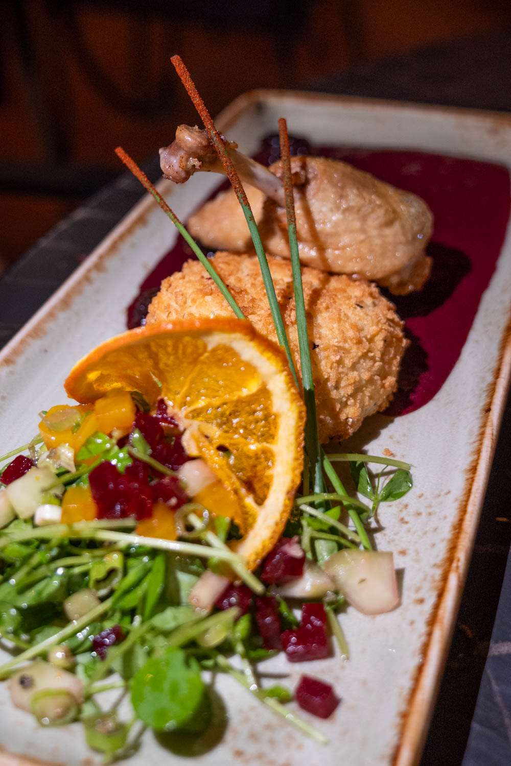 Duck confit and salad on a long rectangular plate