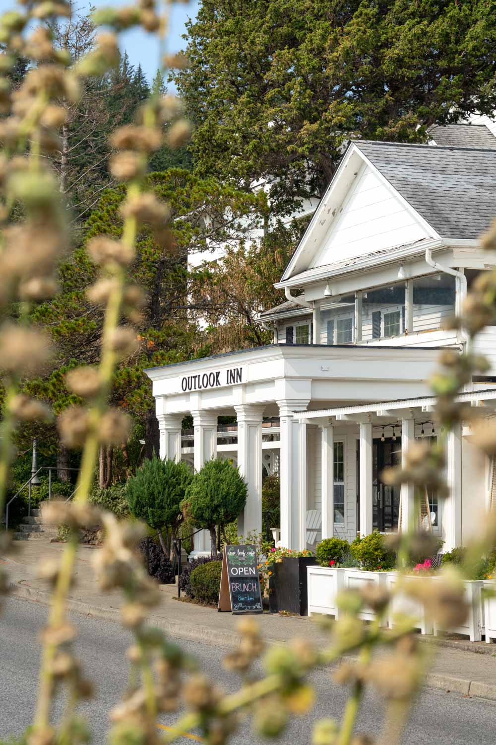 Front of whitewashed Outlook Inn viewed between foilage