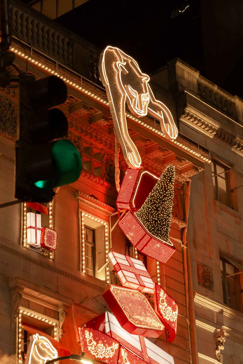 Fifth Avenue holiday lights at night with panther reaching over Cartier storefront, catching a jewellery box open to reveal a Christmas tree
