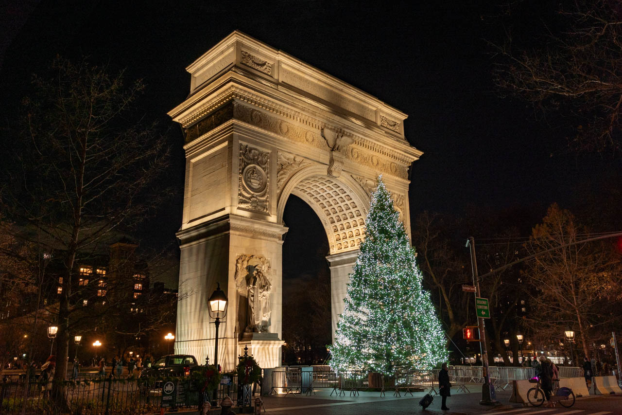 Washington Square Park Christmas Tree illuminated at night, framed by a triumphal arch
