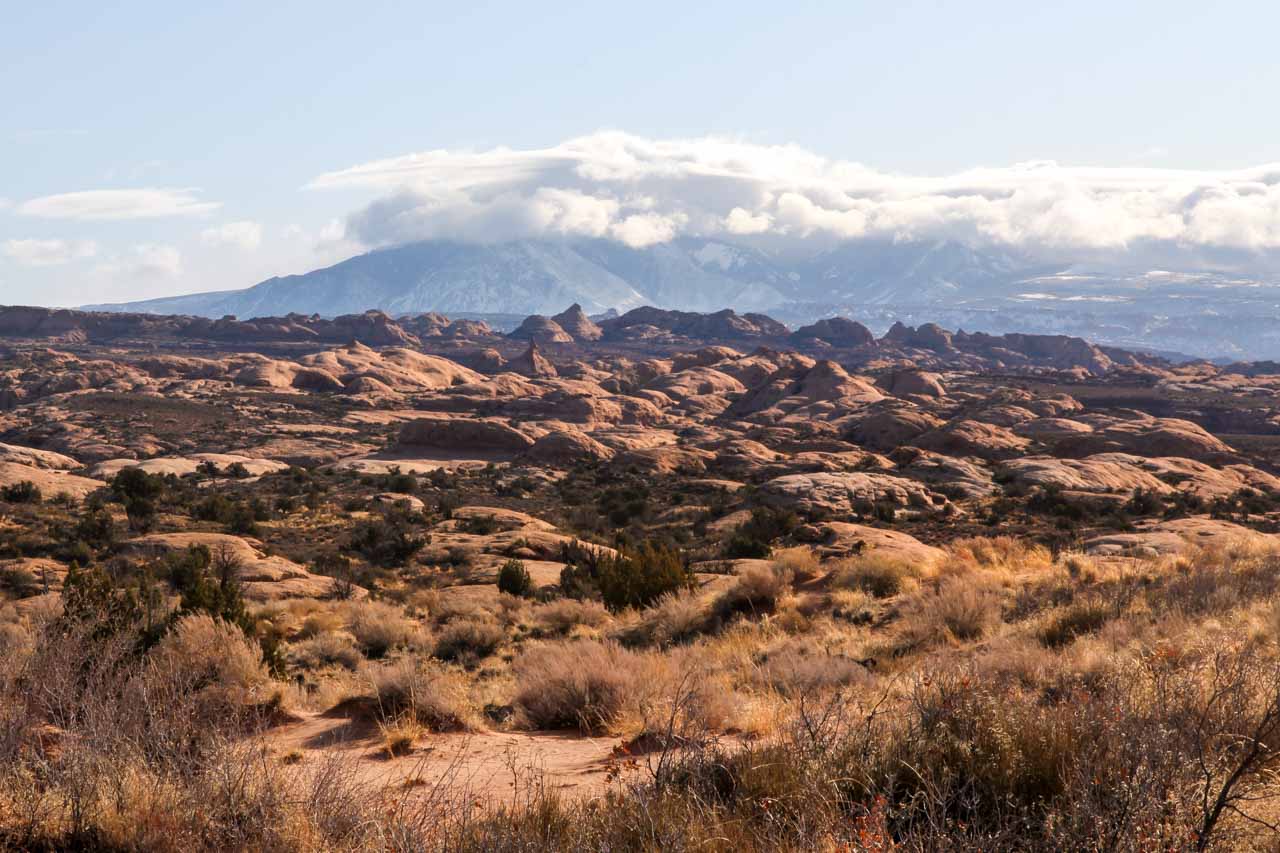Lithified sand dunes with cloud-shrouded La Sal Mountains in the background