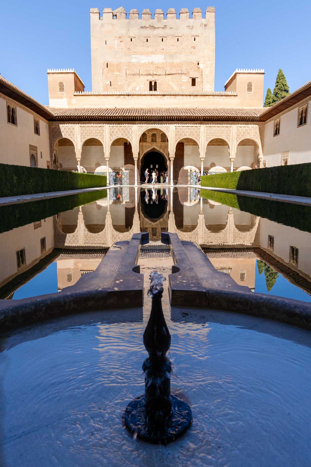 Image of Moorish building reflected in pool with fountain in foreground